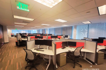 Spacious furnished open office space at Red Brook Corporate Centre featuring modern cubicles, ergonomic chairs, dual-monitor workstations, and large windows allowing natural light — showcasing a move-in-ready “Plug & Play” workspace by David S. Brown Enterprises.